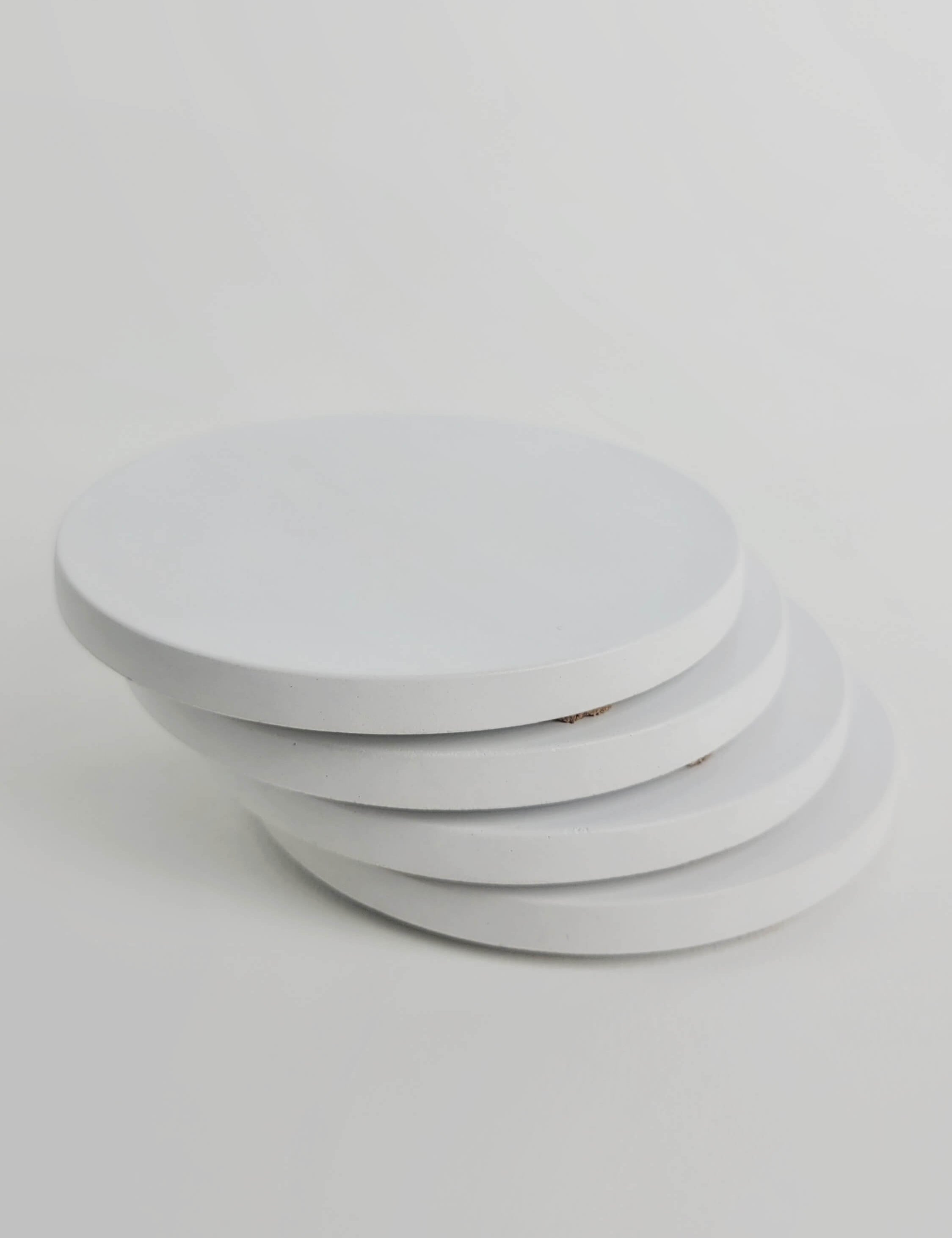 Stack of 4 chalk white concrete coasters, elegantly arranged in a vertical column.