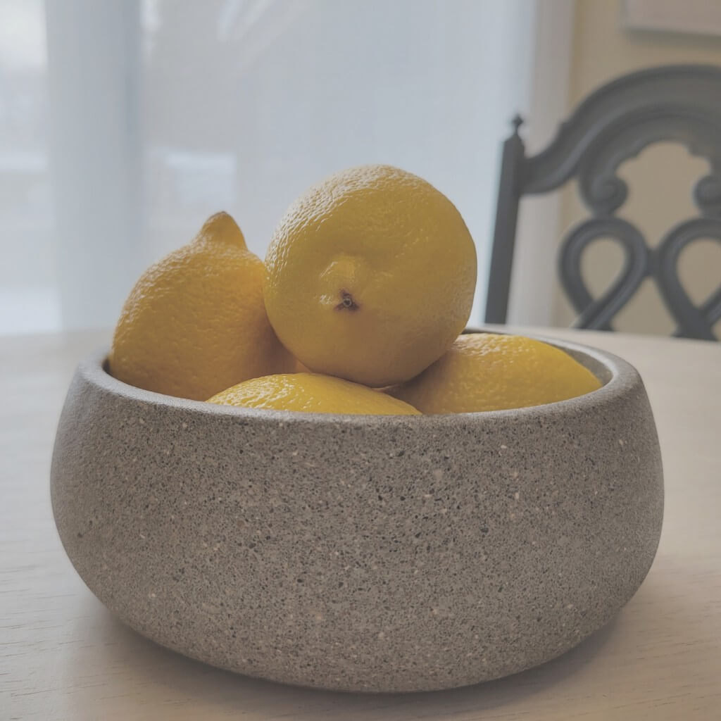 Grey terrazzo stone centerpiece bowl on a table with lemons inside.