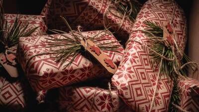 A meticulously arranged pile of rustic, eco-friendly wrapped gifts adorned with natural pine needles and a prominent, uniquely designed label featuring a maple leaf, perfect for festive occasions and sustainable gifting ideas.