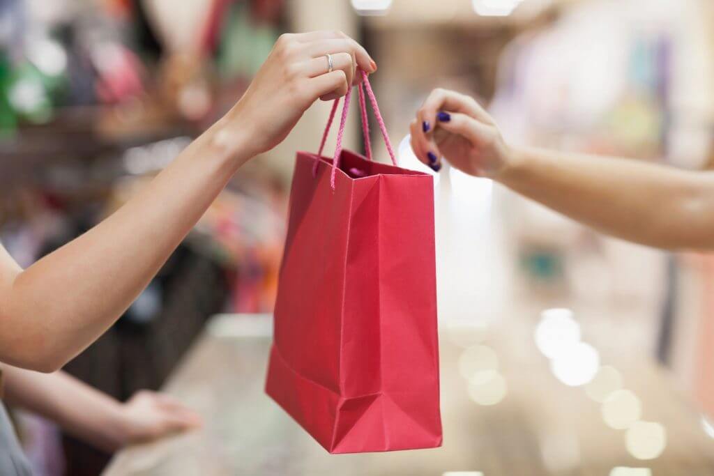 Person giving a red gift bag at an event, showcasing thoughtful gifting and celebration moments.