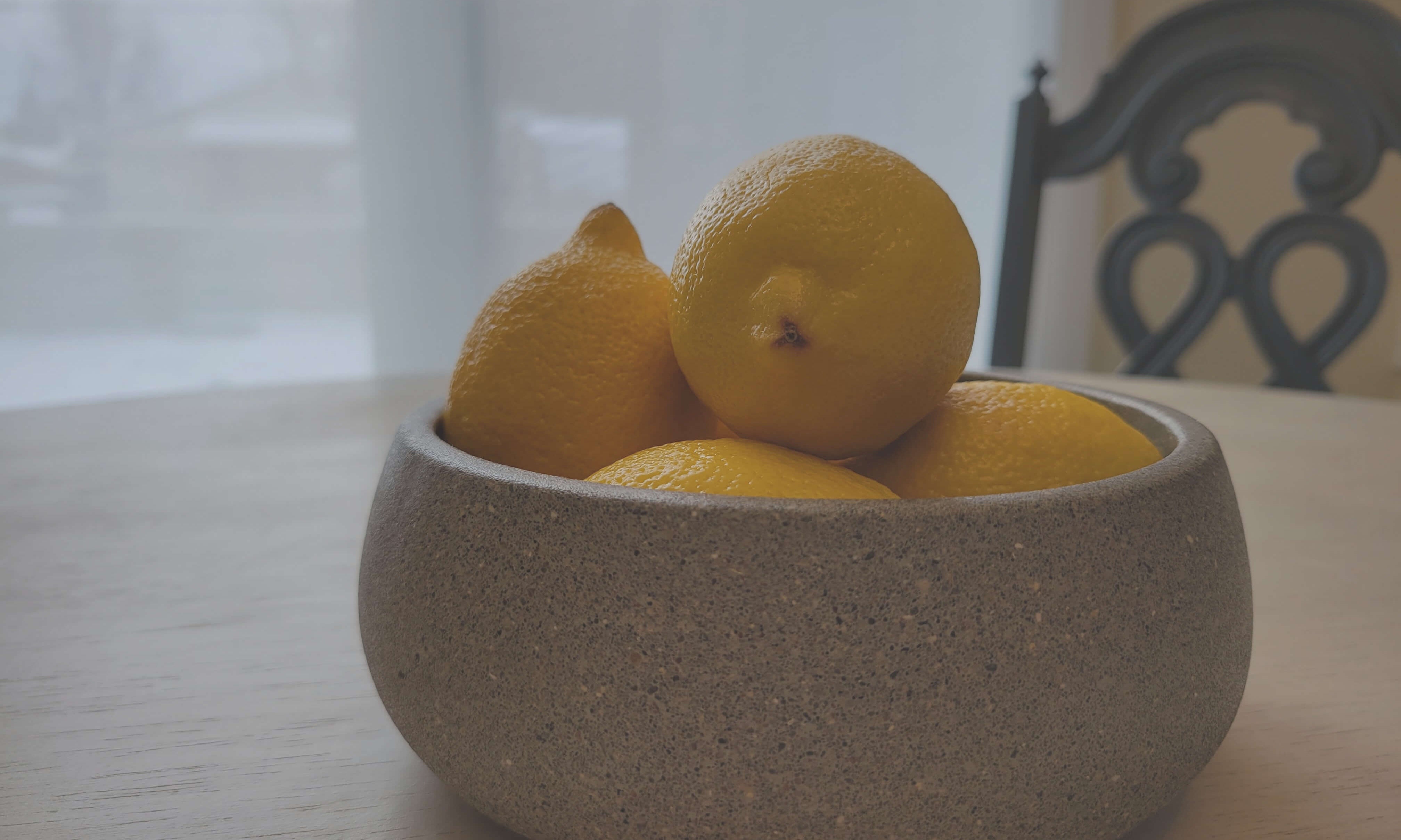 Bright Yellow Lemons in Grey Stone Bowl on Table - Vibrant Kitchen Decor Accessory