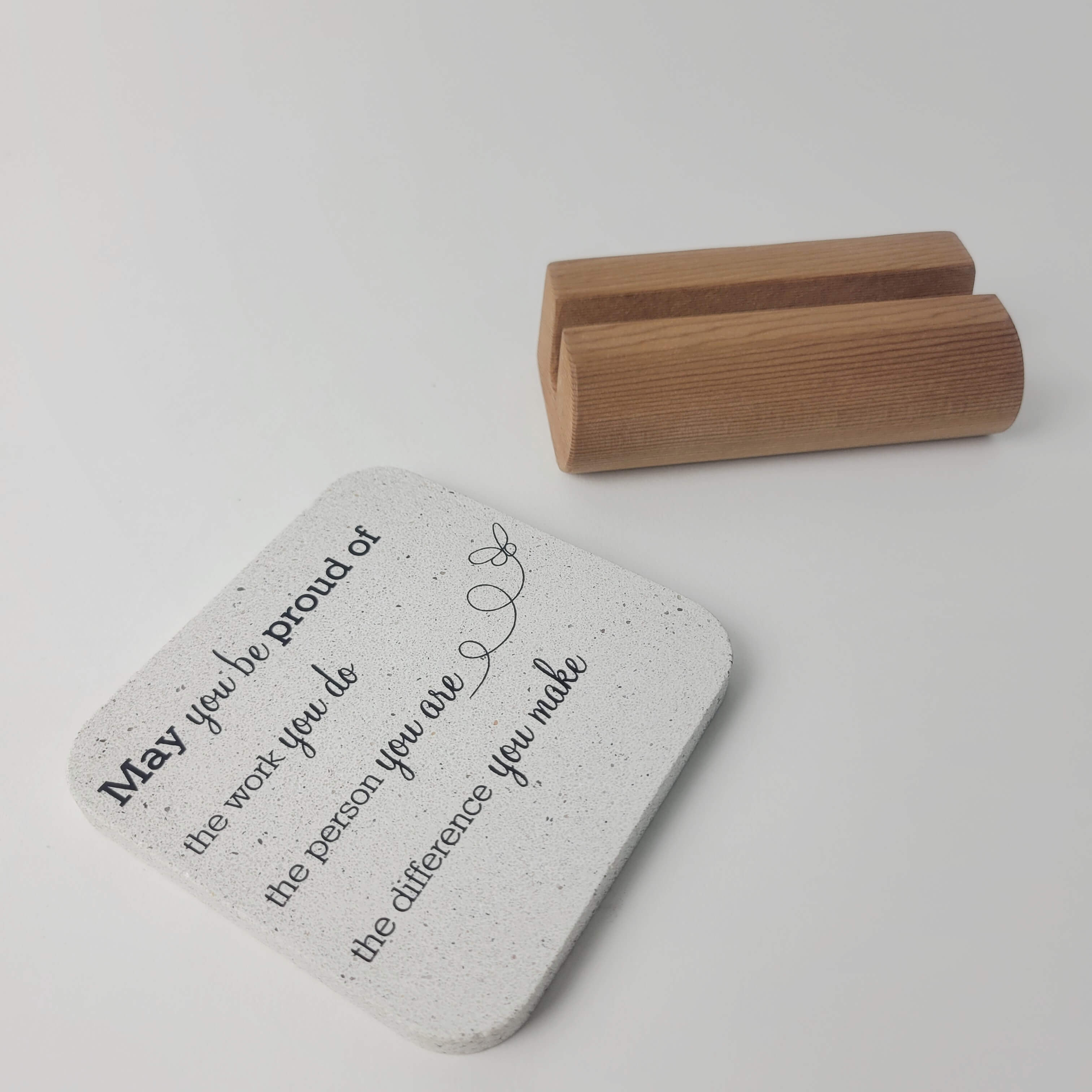White stone motivational mini display 'May you be proud' lying flat in the foreground with notched upcycled western red-cedar base in the background for office and home decor.