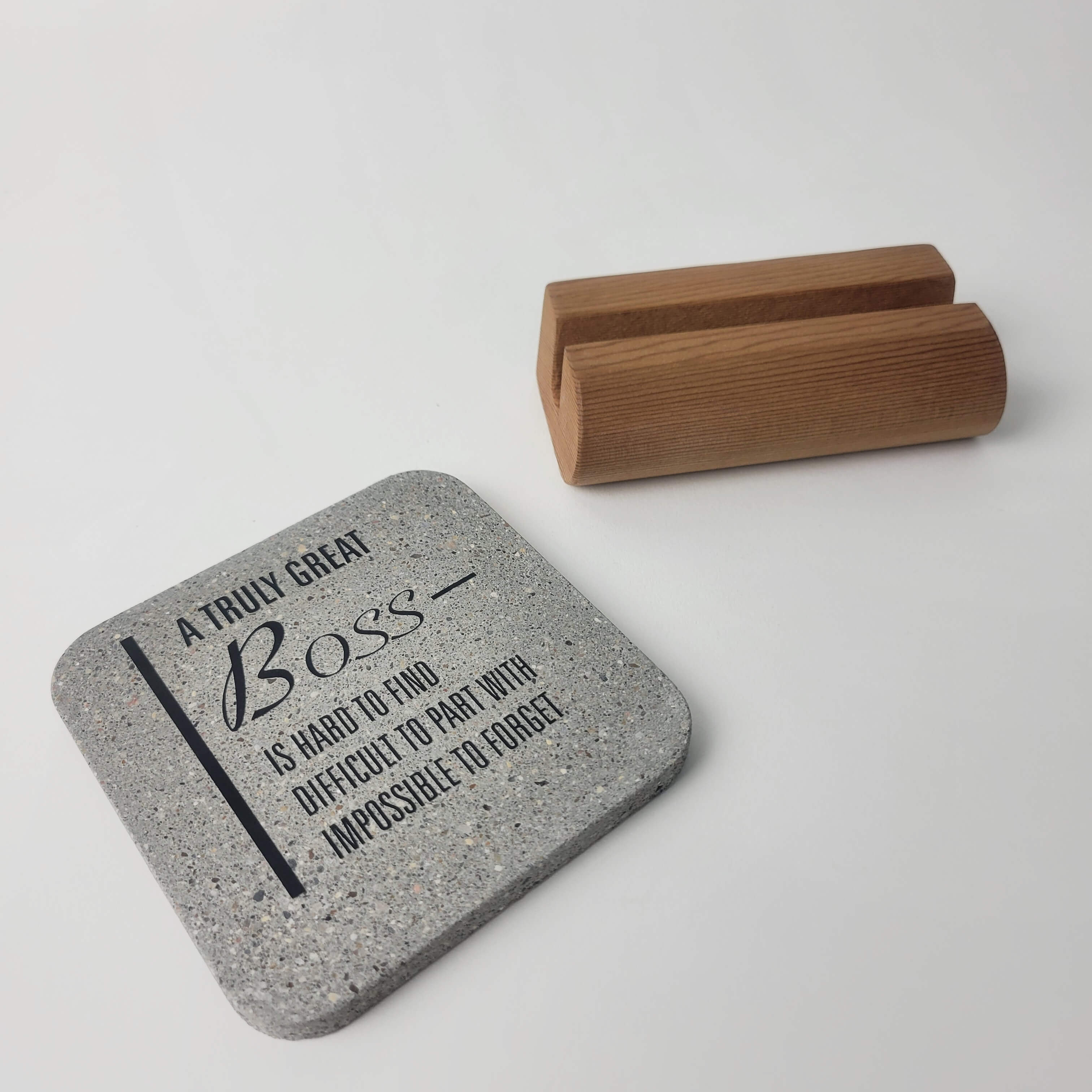 Grey stone motivational mini display 'A truly great boss' lying flat in the foreground with notched upcycled western red-cedar base in the background for office and home decor.