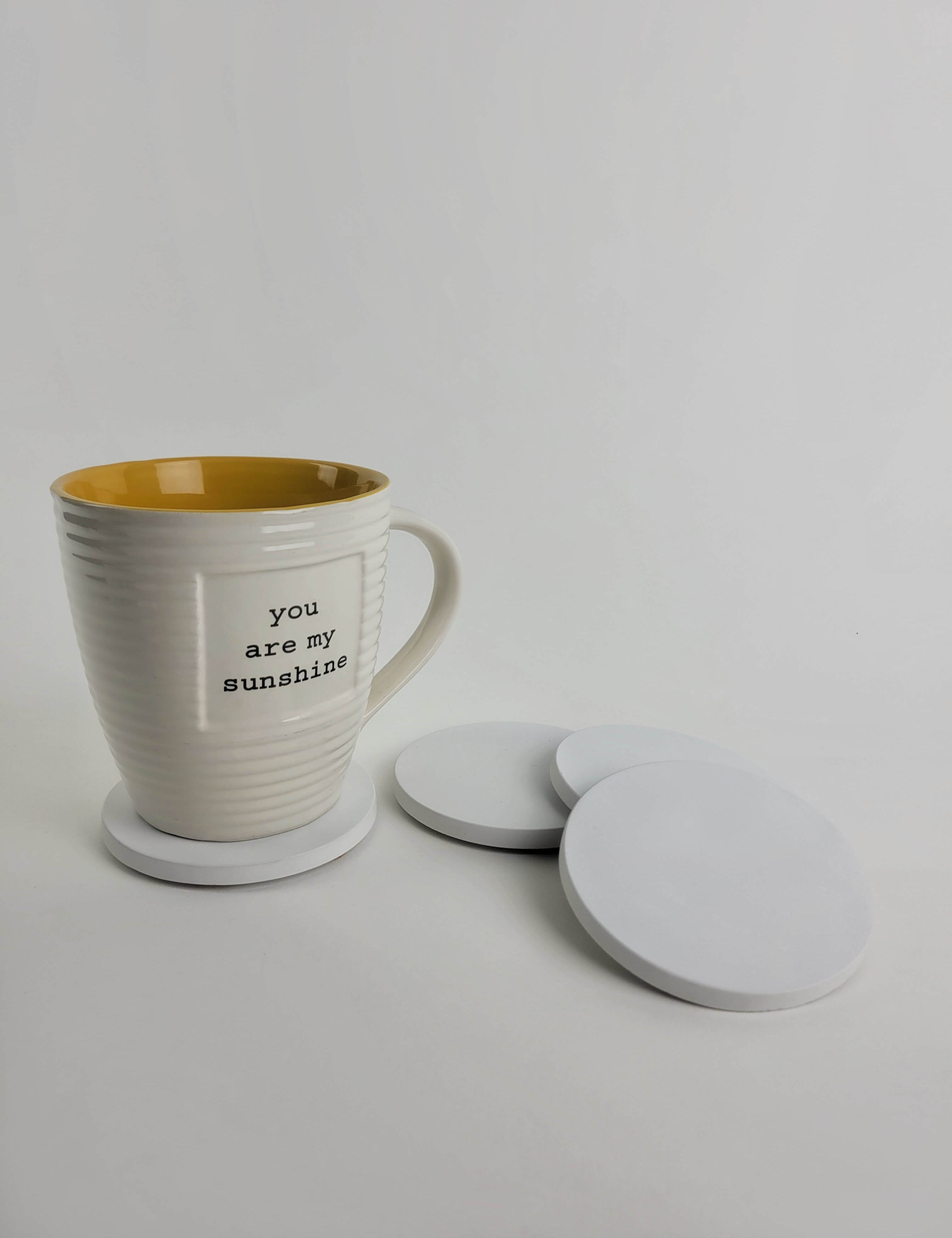 Set of 4 chalk white concrete coasters with a coffee mug resting on one, showcasing elegant home decor.