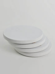 Stack of 4 chalk white concrete coasters, elegantly arranged in a vertical column.