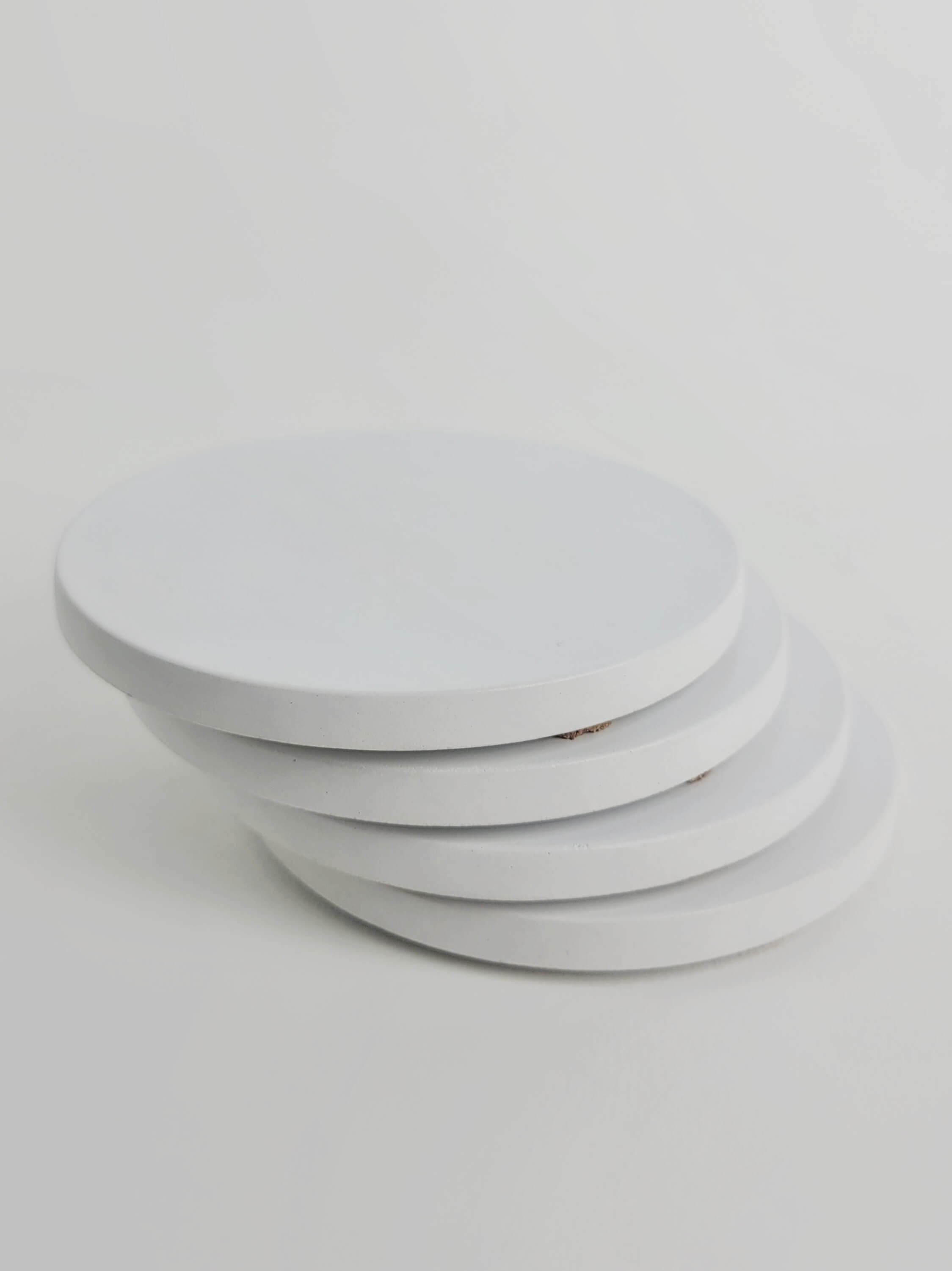 Stack of 4 chalk white concrete coasters, elegantly arranged in a vertical column.