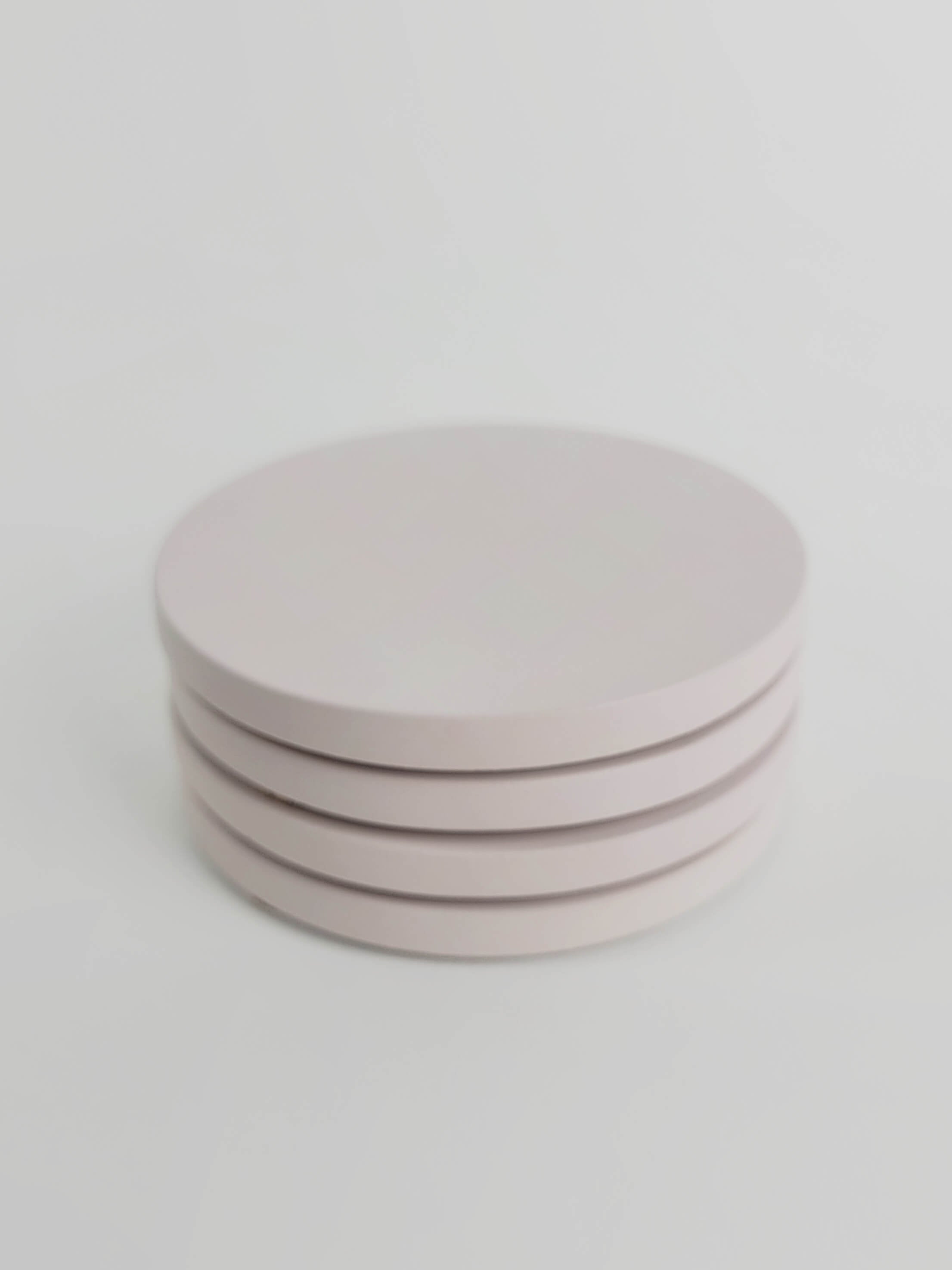 Four pastel pink concrete coasters neatly stacked, highlighting their smooth finish and elegant design.