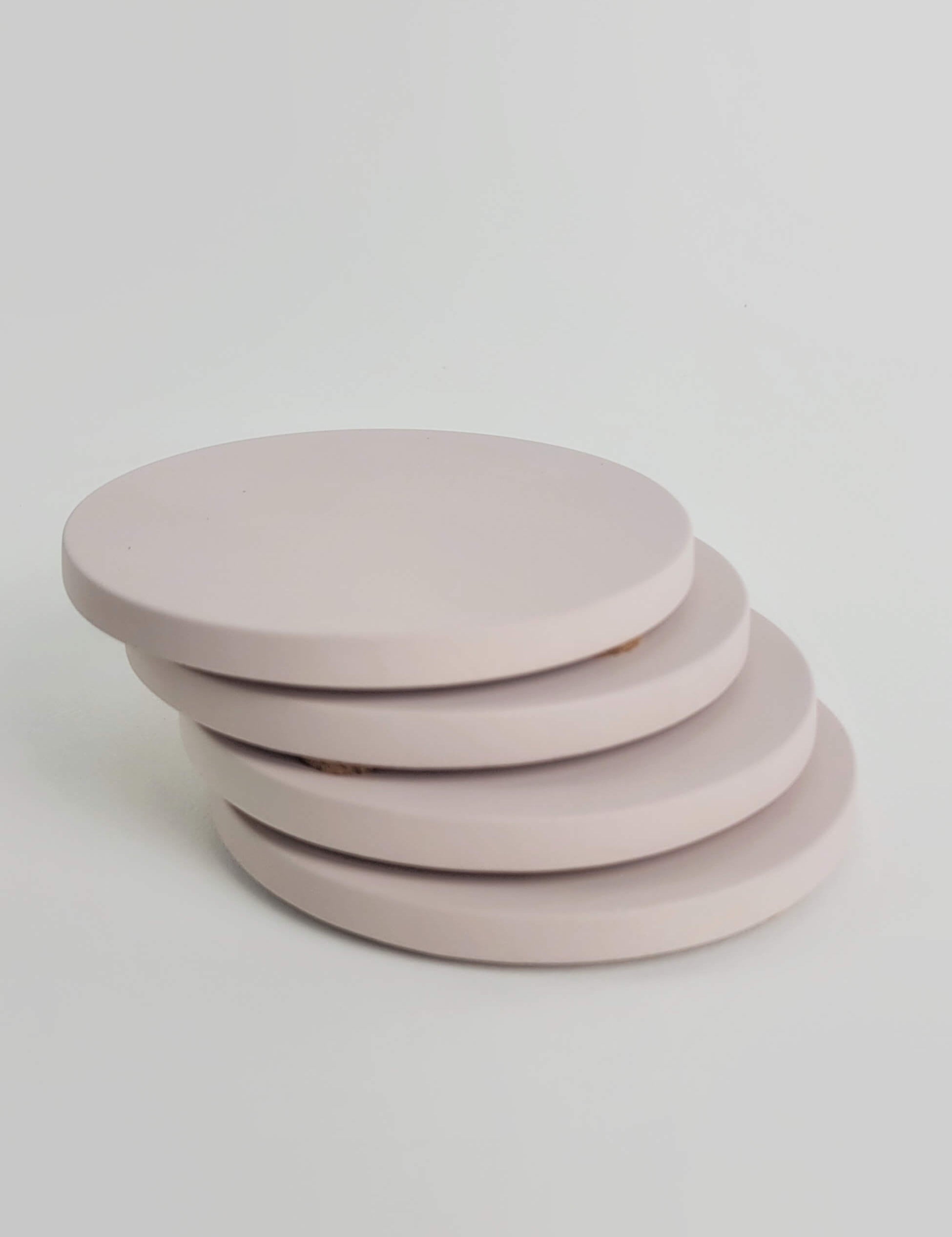 Stack of 4 pastel pink concrete coasters, elegantly arranged in a vertical column.