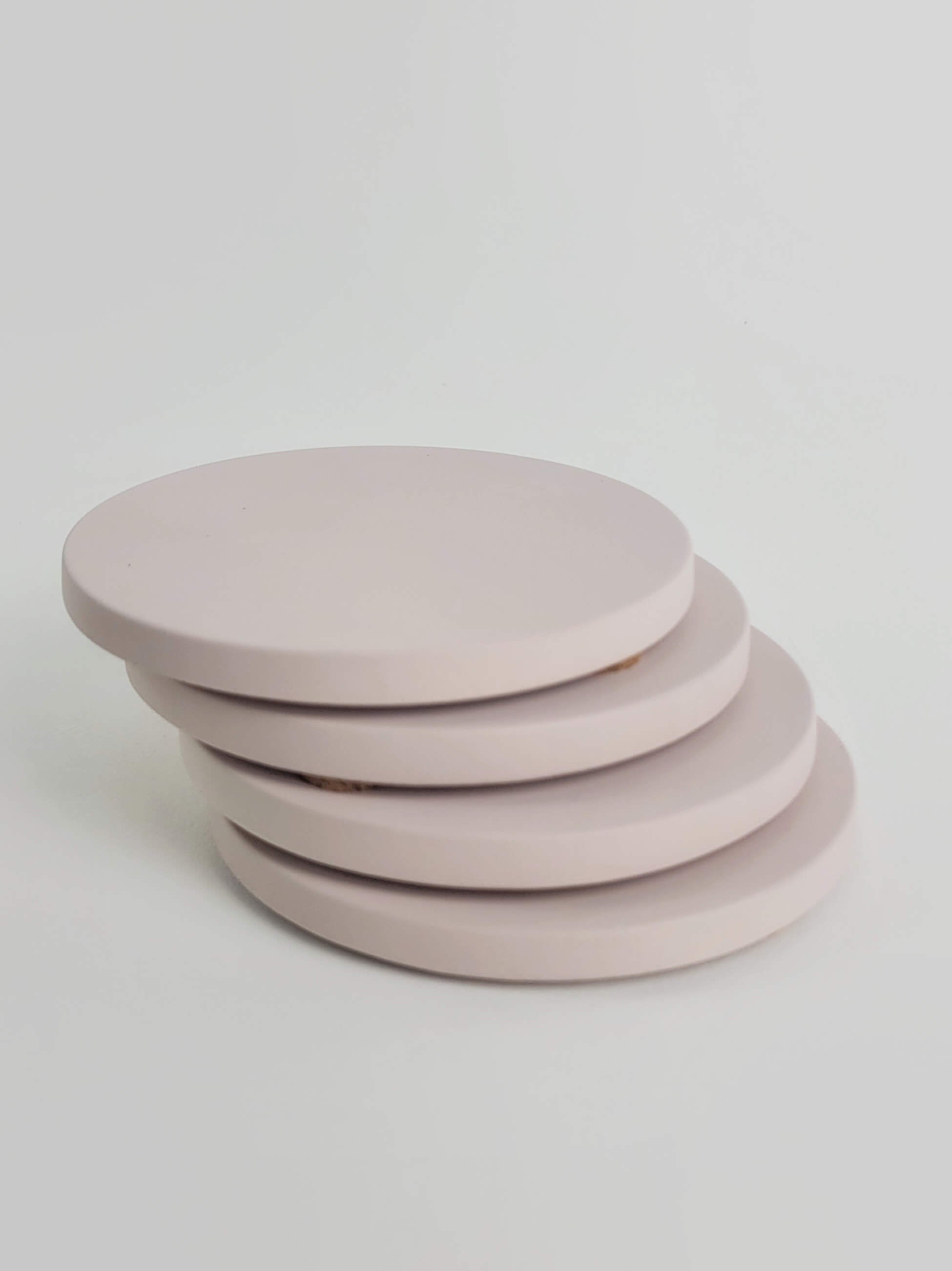 Stack of 4 pastel pink concrete coasters, elegantly arranged in a vertical column.