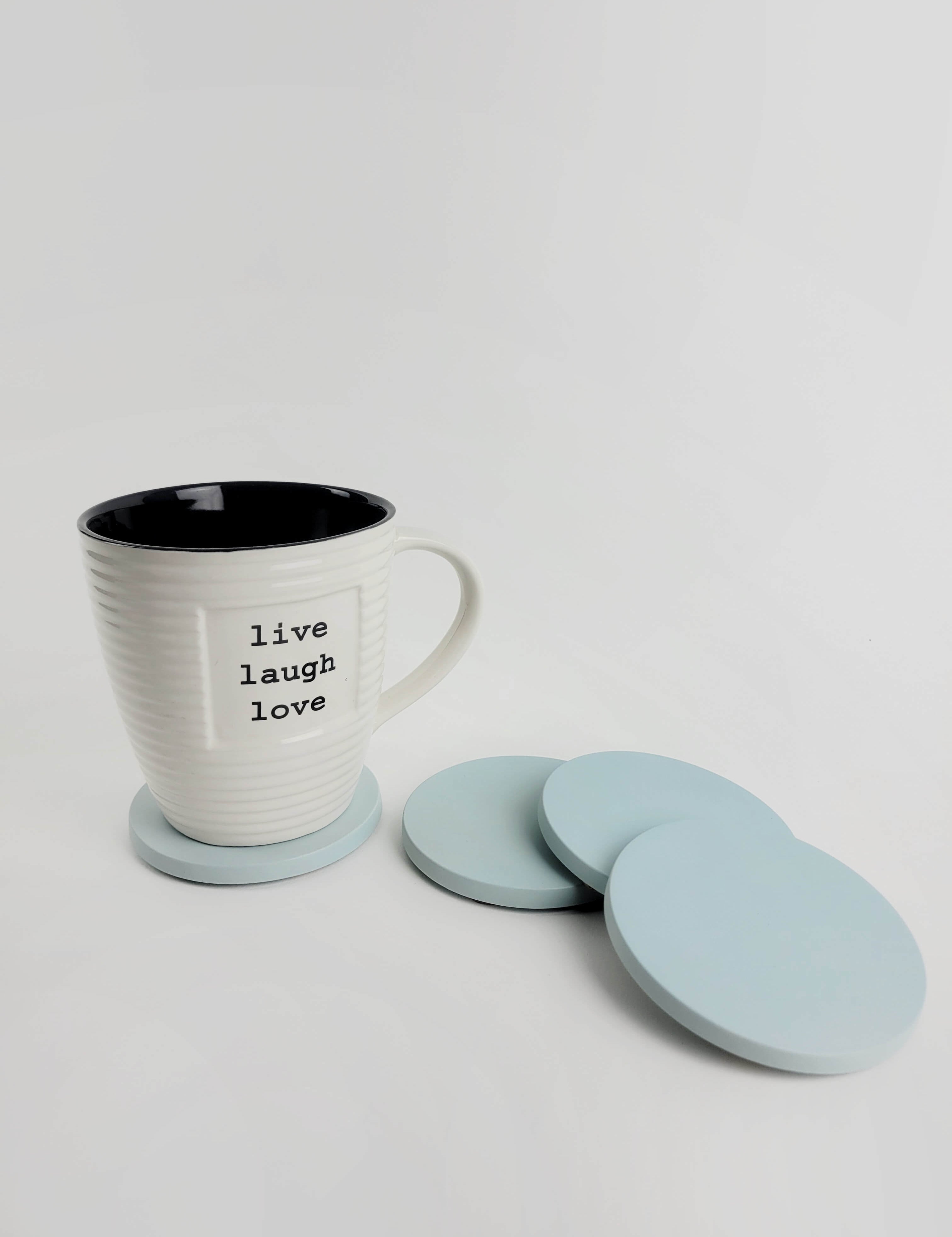 Set of 4 pastel turquoise concrete coasters with a coffee mug resting on one, showcasing elegant home decor.