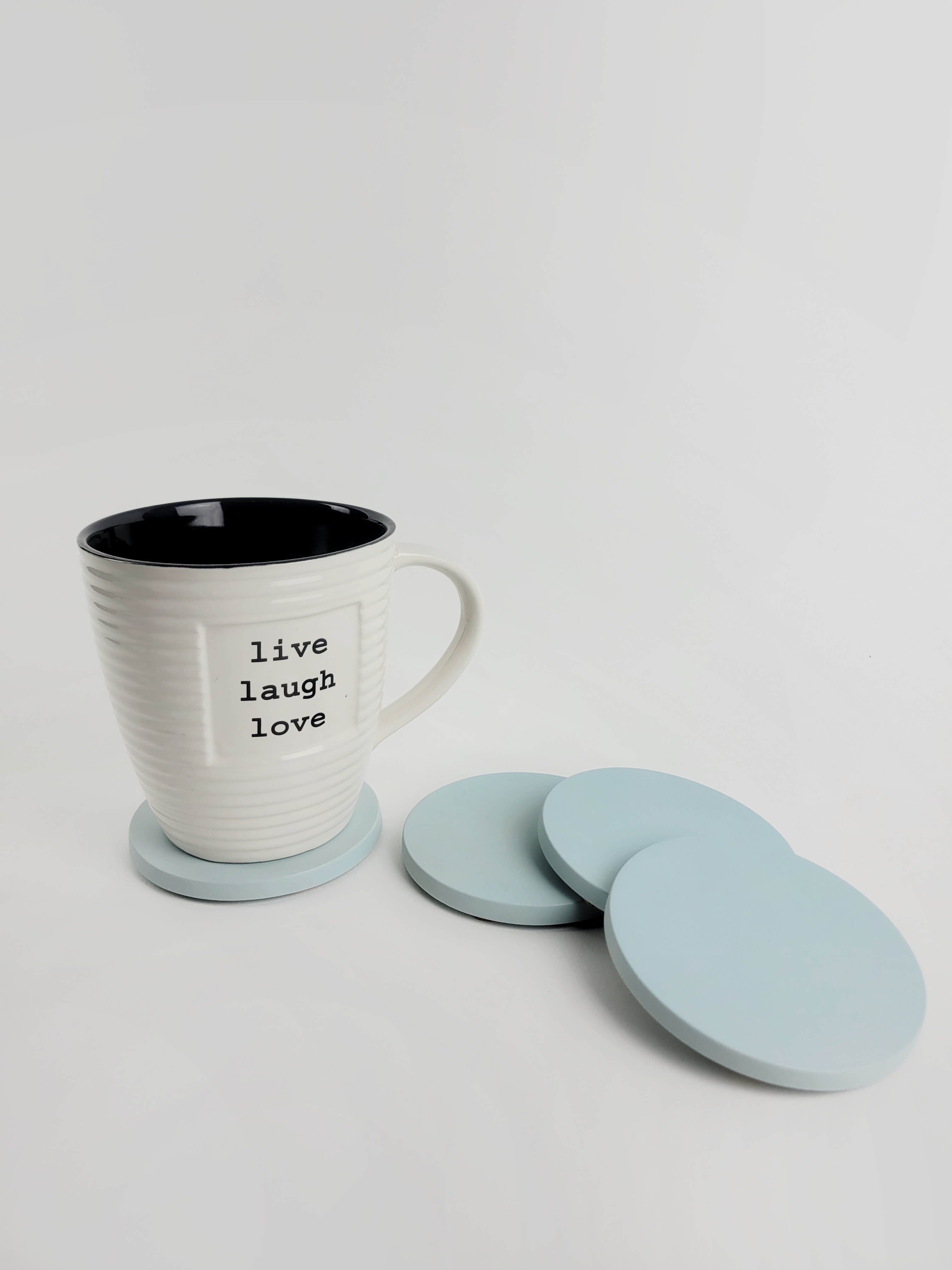 Set of 4 pastel turquoise concrete coasters with a coffee mug resting on one, showcasing elegant home decor.