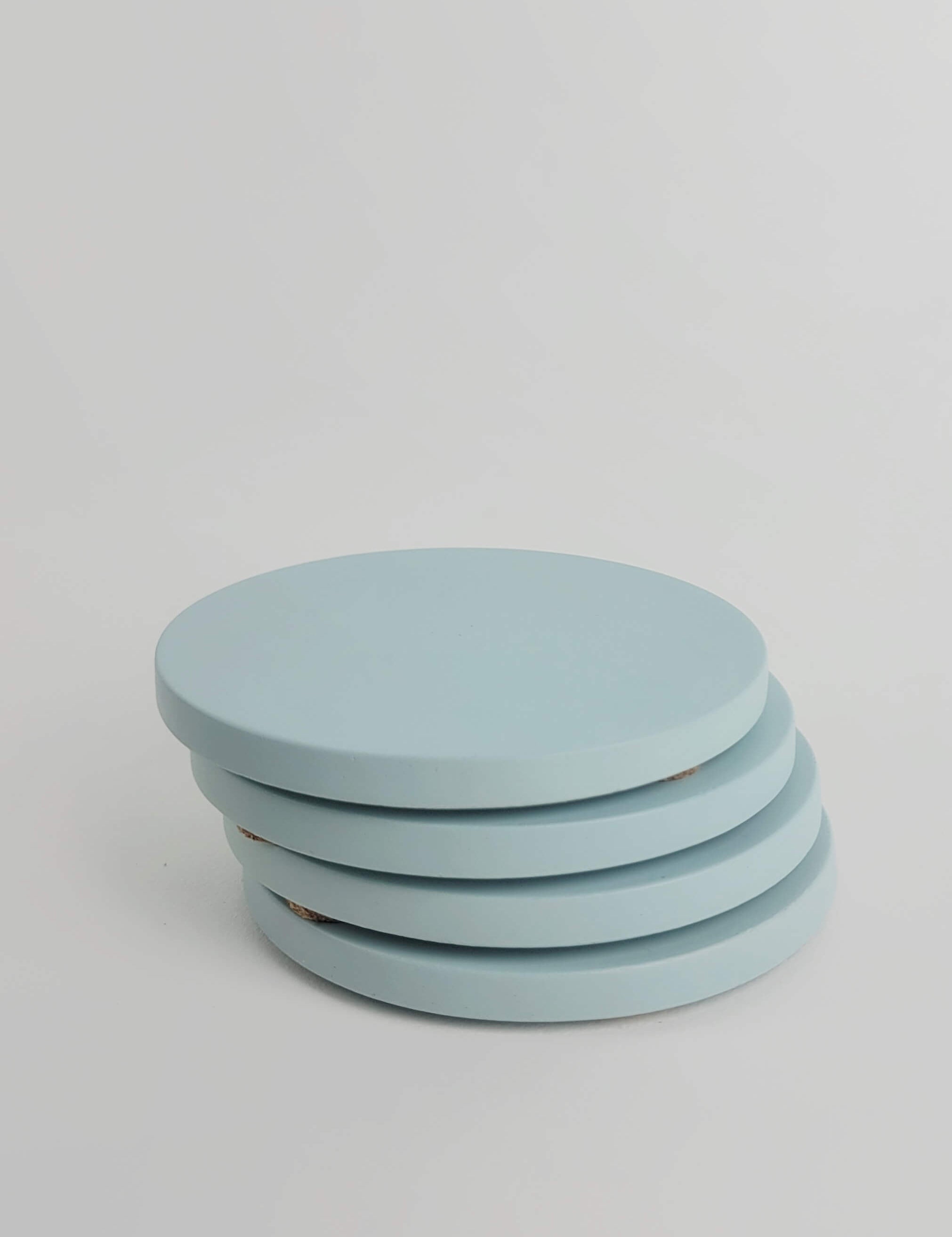 Stack of 4 pastel turquoise concrete coasters, elegantly arranged in a vertical column.