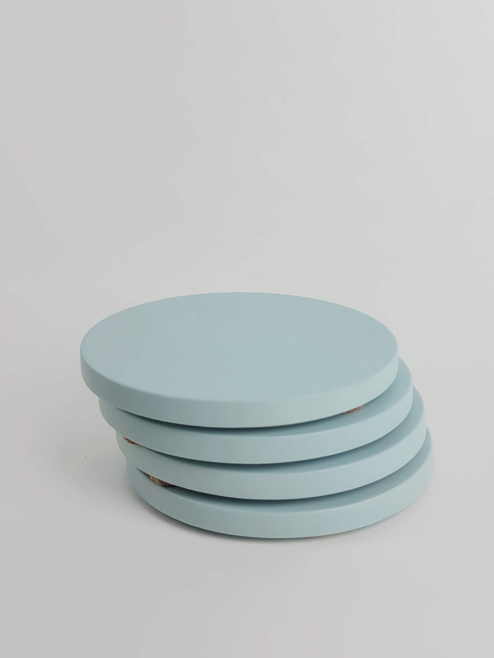 Stack of 4 pastel turquoise concrete coasters, elegantly arranged in a vertical column.