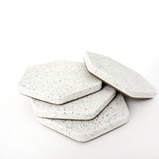 Four white sandstone concrete hexagon coasters displayed loosely stacked on top of eachother.