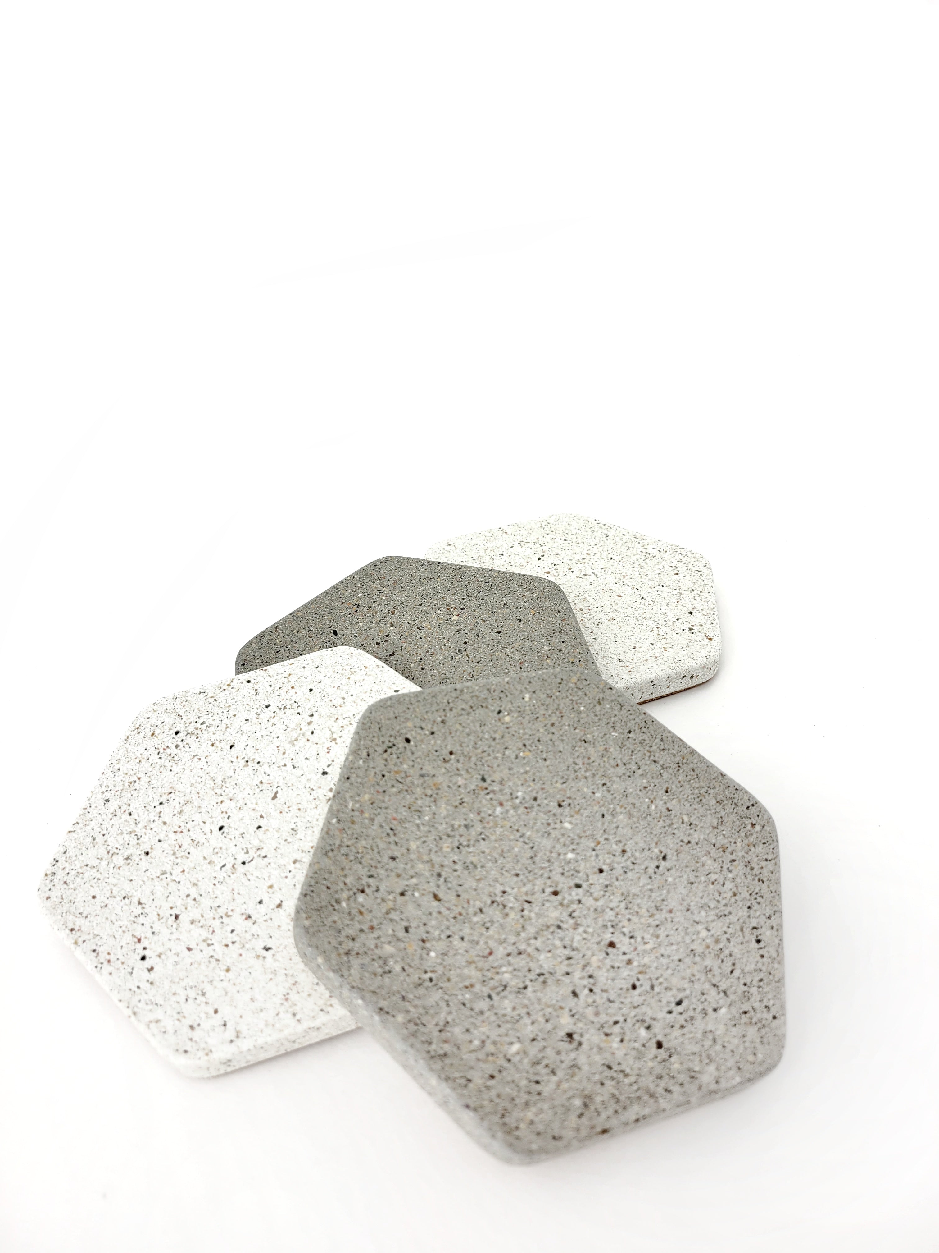 Two grey and two white hexagon sandstone coasters arranged vertically, alternating between grey and white.