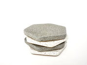Stack of two grey and two white sandstone hexagon coasters, alternating their colors.