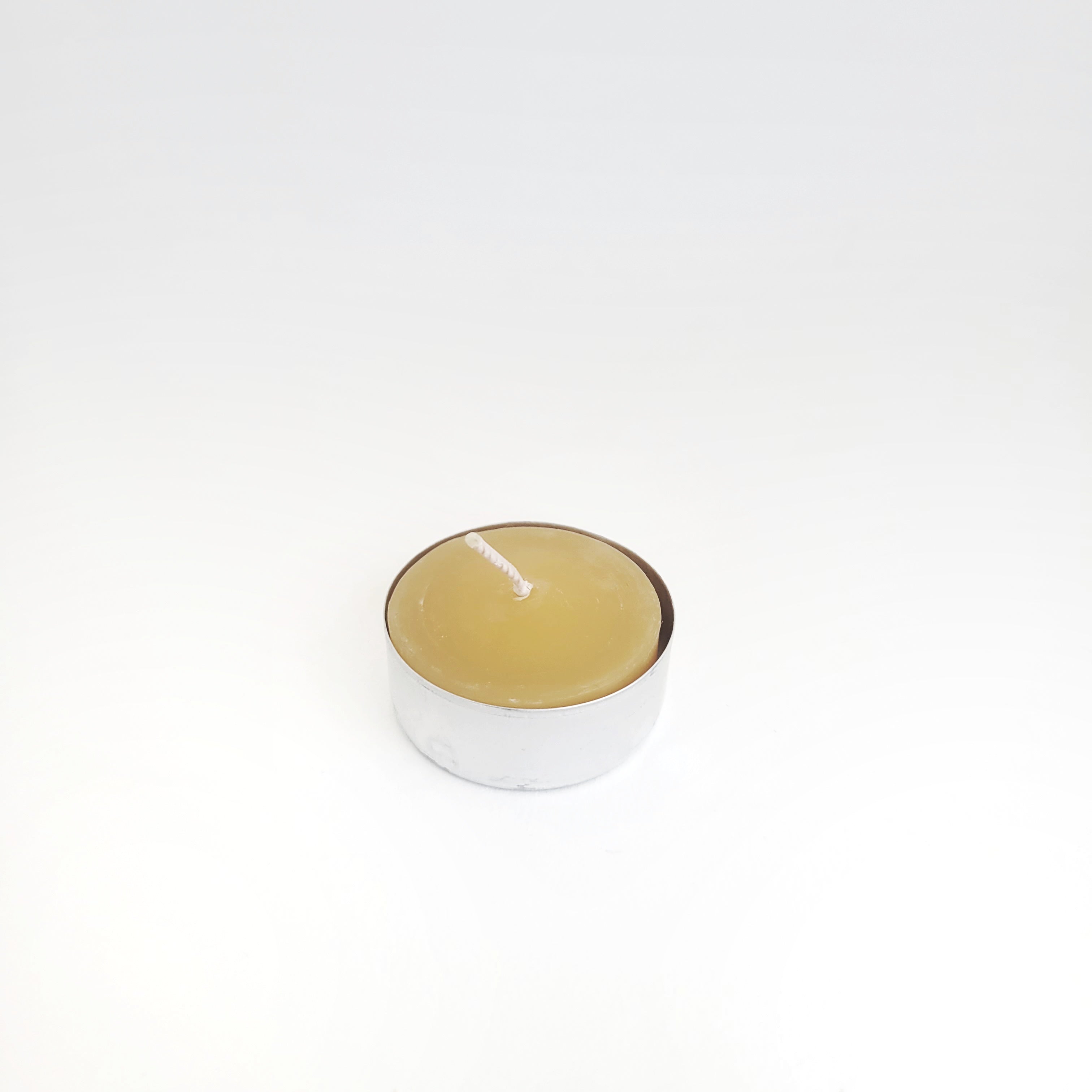 Single natural honey-colored beeswax tealight in a tin cup, perfect for eco-friendly home decor and ambiance.