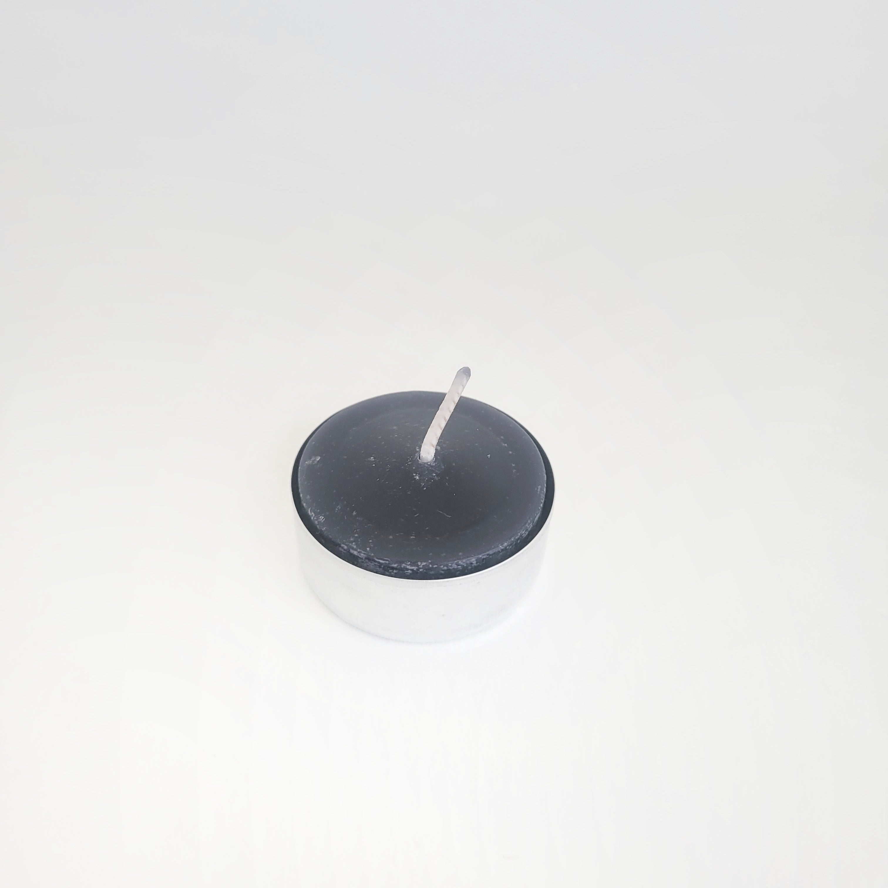 Single beeswax tealight in a tin cup, with a striking black color, perfect for eco-friendly home decor and ambiance.