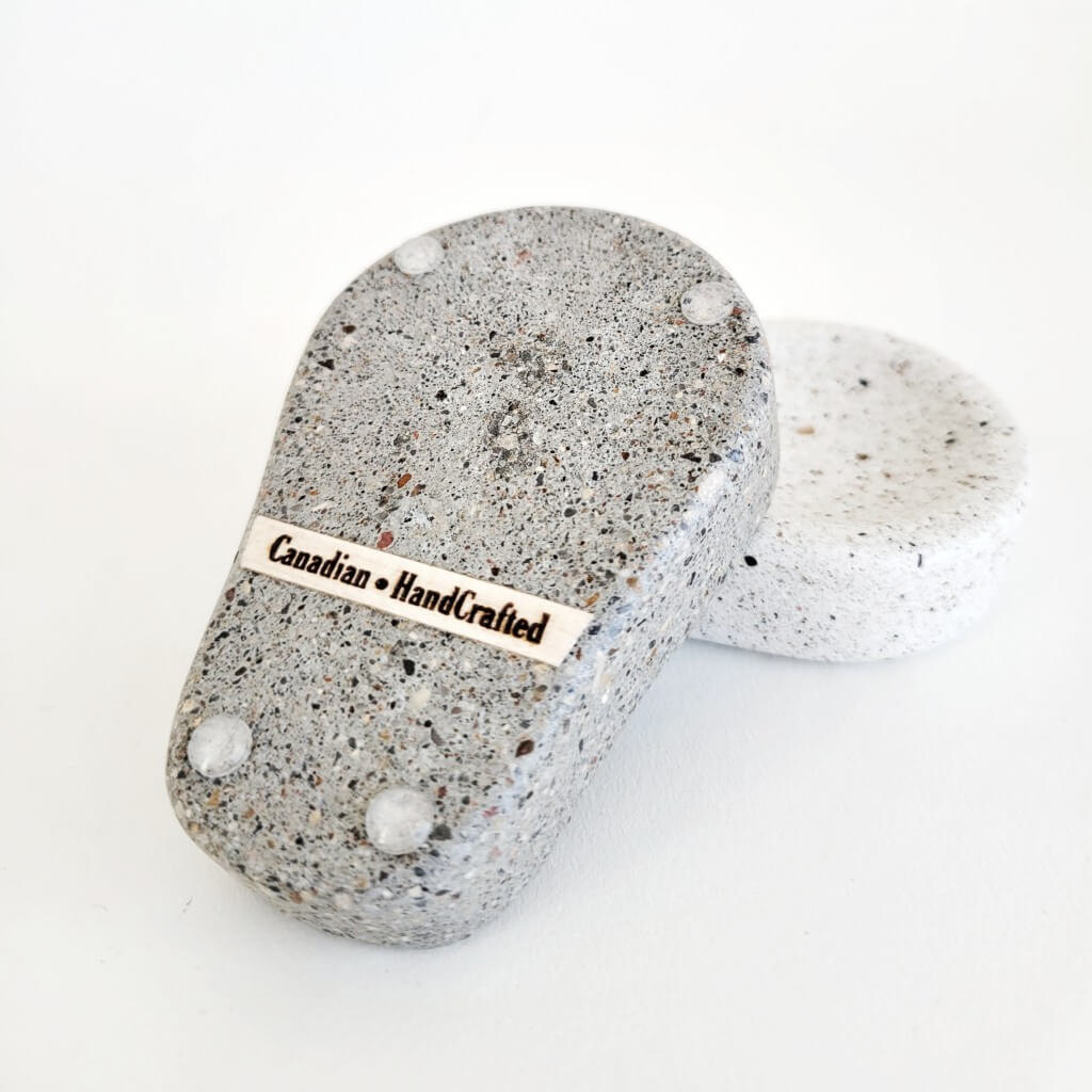 Canadian HandCrafted engraved in the bottom of a grey stone spoon rest. There are clear vinyl bumpers attached to 4 corners.