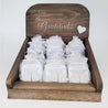 Gratitude Gift Pre-Pack Counter Display made from dark stained wood with silver lettering reading "a gift of gratitude" engraved in it. A white stone heart is attached to the front of the display. The display is filled with 24 silver translucent baggies each baggie contains two stone hearts and two gratitude notes. There is a gold engraving in the lower section of the display reading "Canadian HandCrafted"
