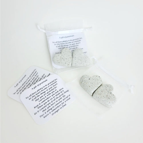 Two stone hearts and notes in a translucent silver baggie, embodying gratitude. Below, another set of stone hearts and notes, highlighting the act of sharing appreciation and love.