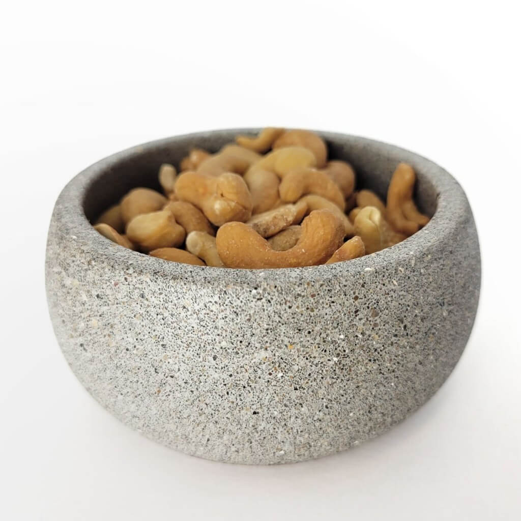Grey stone centerpiece nut bowl with cashews inside.