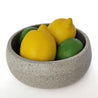 Large grey sandstone centerpiece bowl with lemons and limes inside.